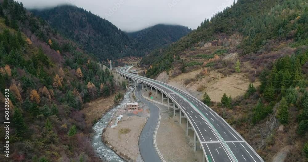 Winding elevated highway in the beautiful valley of an aerial view.Beautiful tree covered valley with winding roads and flowing streams.The valley dotted with convenient traffic and a winding river. Winding elevated highway in the beautiful valley of an aerial view.Beautiful tree covered valley with winding roads and flowing streams.The valley dotted with convenient traffic and a winding river.