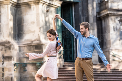couple of young, stylish tourists dancing on street in sunlight