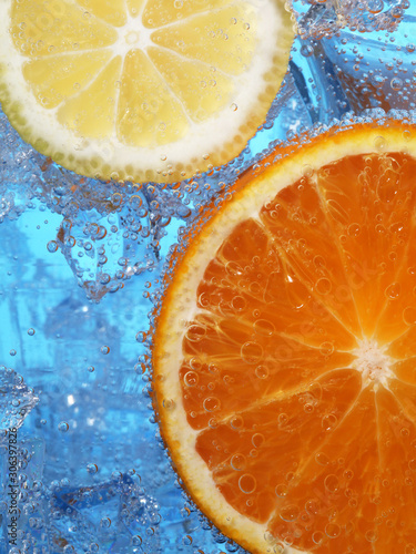 Front view of citrus fruits in bubbles on blurred blue ice water background