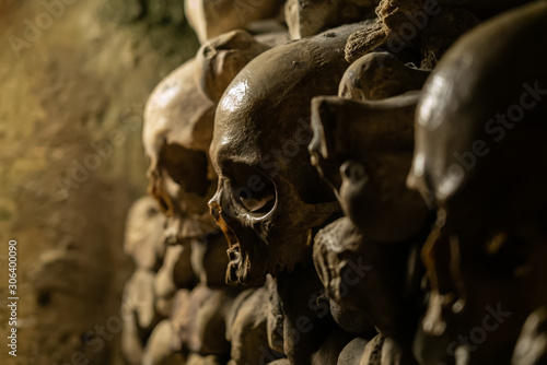 Skulls and bones in catacombs. Old broken skull placed in the wall of bones. Grim lighting. Underground cemetery photo