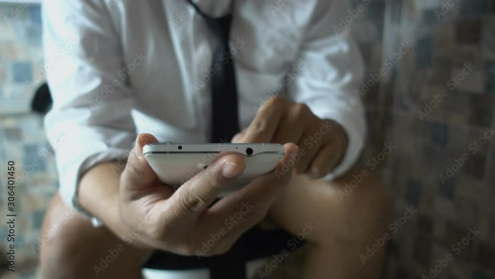 Businessman using smart phone in toilet Businessman using smart phone in toilet