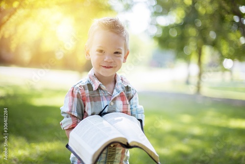 Photography Closeup shot of a child holding an open bible while looking at the camera with b