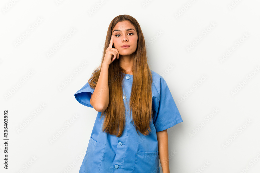 Young caucasian nurse woman pointing temple with finger, thinking, focused on a task. Young caucasian nurse woman pointing temple with finger, thinking, focused on a task.