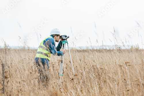 Tableau sur toile Side view of surveyor with digital level measuring field