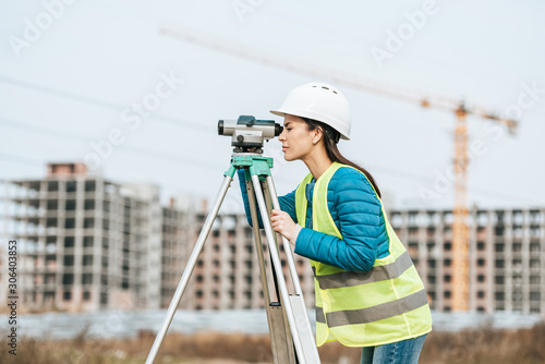Side view of Surveyor measuring land with digital level