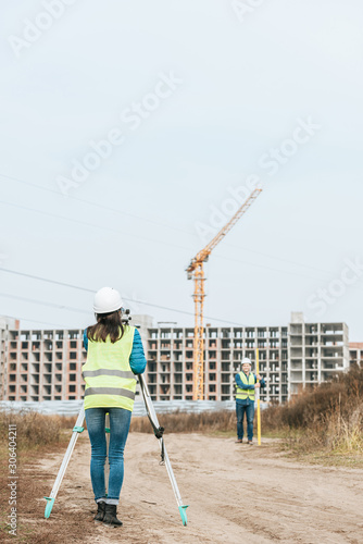Surveyors measuring land on dirt road of construction site