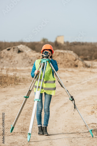 Female surveyor using digital level on dirt road