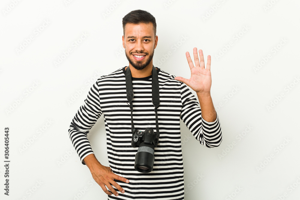 Fototapeta premium Young south-asian photographer smiling cheerful showing number five with fingers.