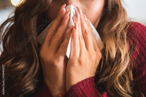Flu cold or allergy symptom.Sick young woman  sneezing in tissue, allergies, headaches. photo