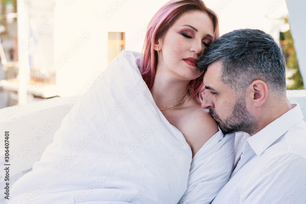 portrait of a beautiful young couple on a balcony on a background of the old city. romantic breakfast. girl in a blanket on the balcony. honeymoon. lovers. date portrait of a beautiful young couple on a balcony on a background of the old city. romantic breakfast. girl in a blanket on the balcony. honeymoon. lovers. date