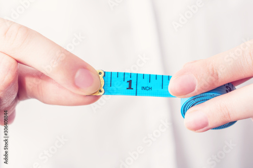 Wallpaper Mural Girl with tape measure shows 1 inch length, female hand, close up, cropped image, toned Torontodigital.ca