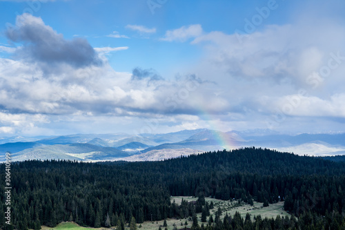 Montenegro  Colorful rainbow over black conifers of alpine forest on highlands of durmitor national park nature landscape at dawn from mountain top of curevac near zabljak