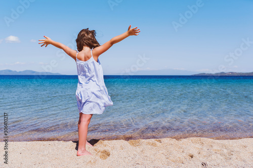 Cute little girl looking at sea on beautiful tropical beach. Summer, fun and vacations concept