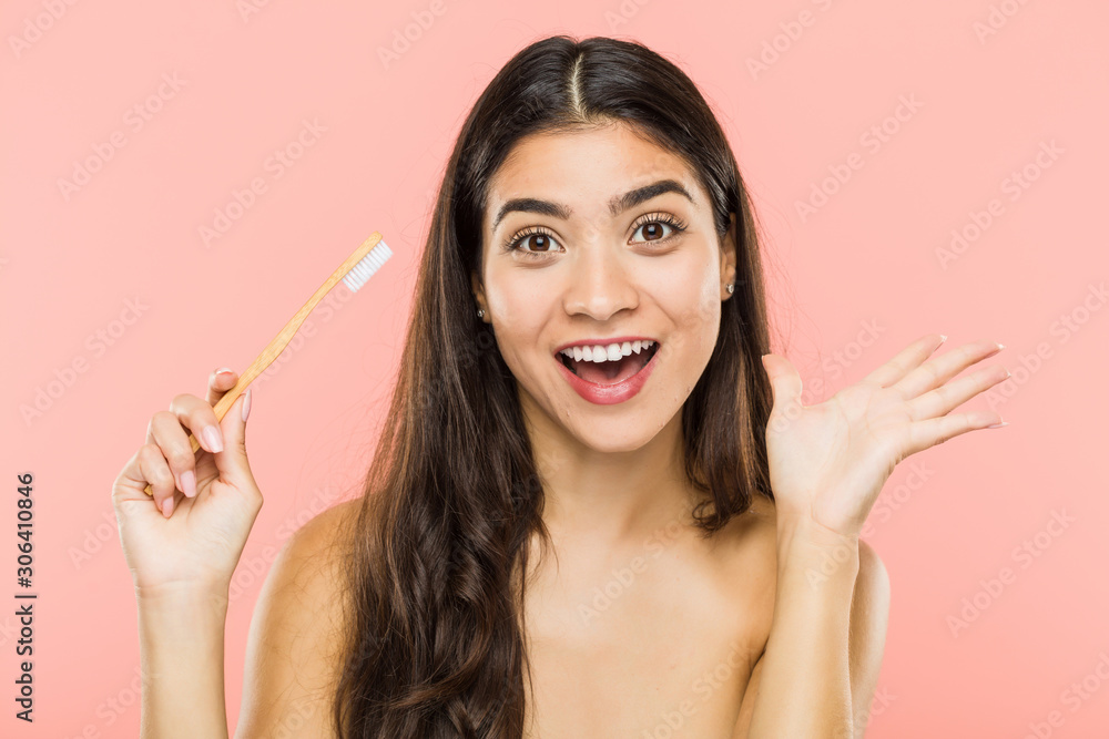 Young indian woman holding a toothbrush celebrating a victory or success Young indian woman holding a toothbrush celebrating a victory or success