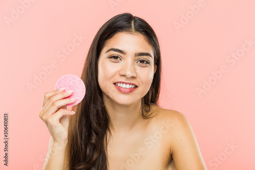 Young indian woman holding a facial skin care disc happy, smiling and cheerful.