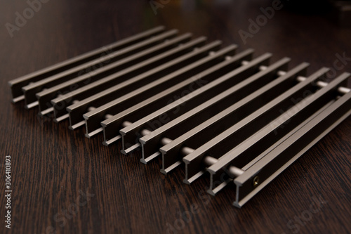 On a dark table lies a lattice of bronze-colored metal strips connected by inserts.