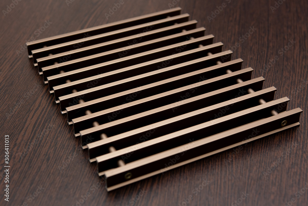 On a dark table lies a grate of chocolate-burgundy metal planks connected by inserts. On a dark table lies a grate of chocolate-burgundy metal planks connected by inserts.