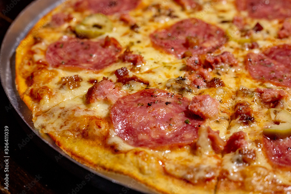 Homemade hot pepperoni pizza ready to eat on a wooden table and aluminum tray Homemade hot pepperoni pizza ready to eat on a wooden table and aluminum tray
