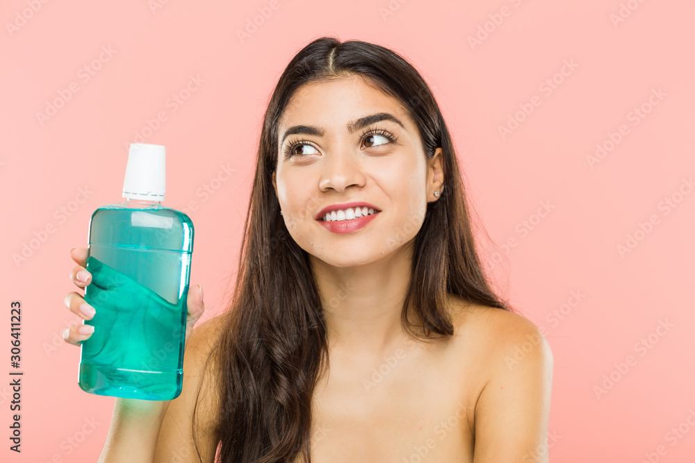 Young indian woman holding a mouthwash bottle smiling confident with crossed arms. Young indian woman holding a mouthwash bottle smiling confident with crossed arms.