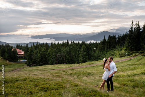 A man and a woman hug and look at each other against the backdrop of the forest