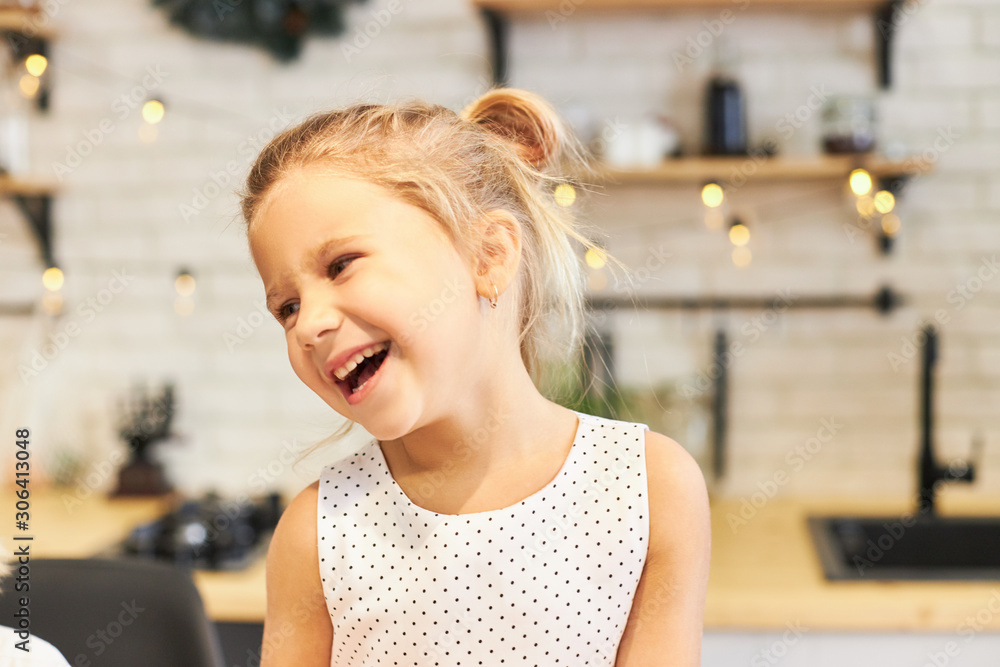 Happy beautiful five year old little girl in nice dress smiling broadly while sitting at dining table in festive atmosphere, having Thanksgiving dinner together with her family, garland in background Happy beautiful five year old little girl in nice dress smiling broadly while sitting at dining table in festive atmosphere, having Thanksgiving dinner together with her family, garland in background