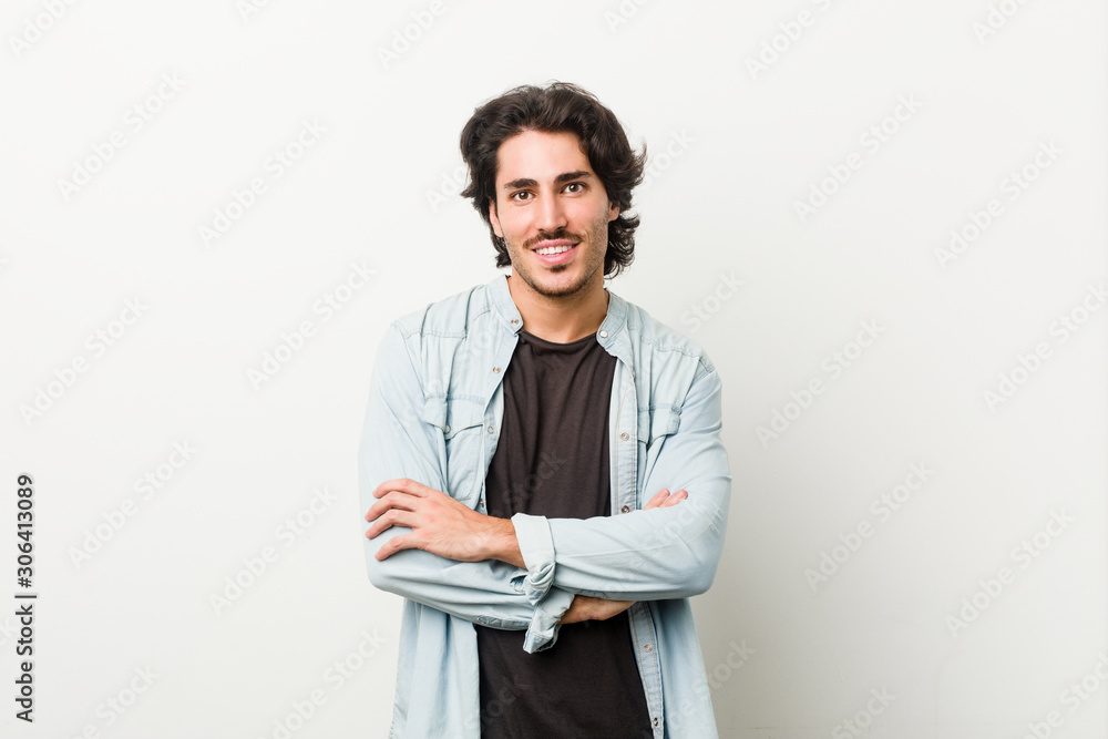 Young handsome man against a white background who feels confident, crossing arms with determination. Young handsome man against a white background who feels confident, crossing arms with determination.