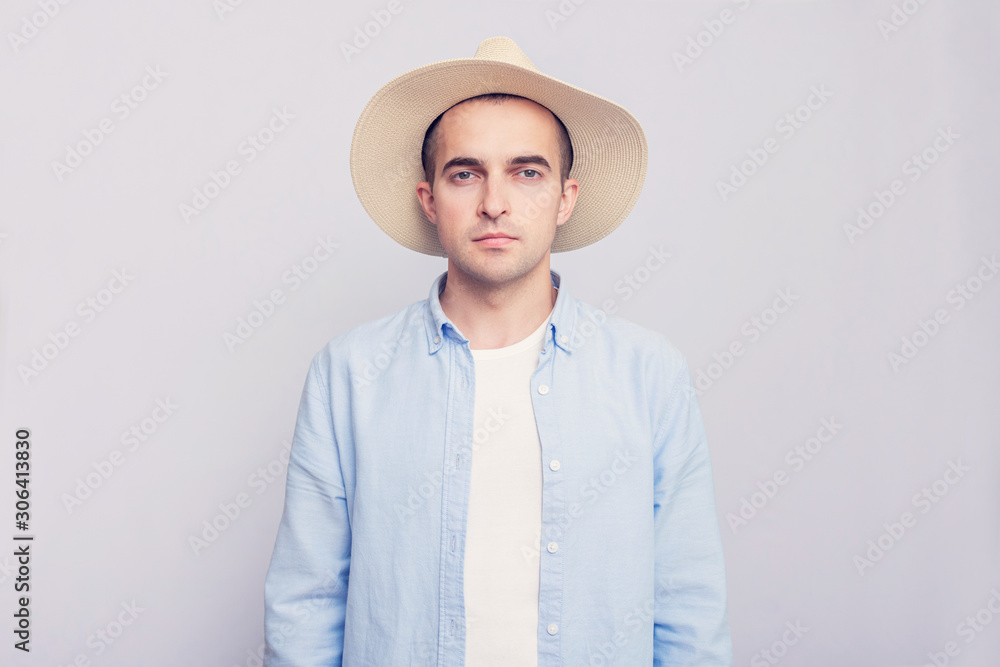 Handsome man in hat looking at camera, grey background portrait, copy space, toned Handsome man in hat looking at camera, grey background portrait, copy space, toned