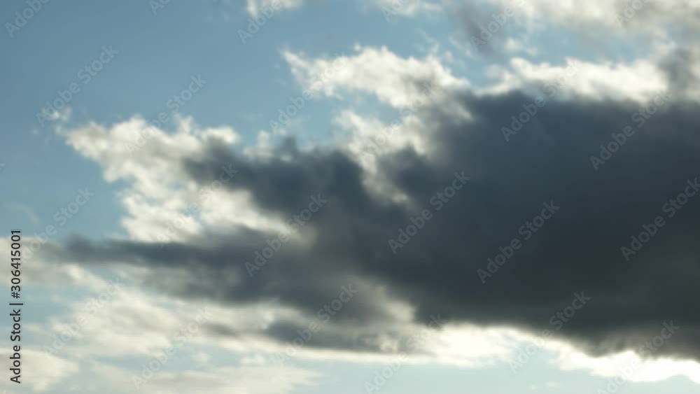 Big dark clouds lit by the rays of the sun, are floating in the blue sky, time lapse Big dark clouds lit by the rays of the sun, are floating in the blue sky, time lapse