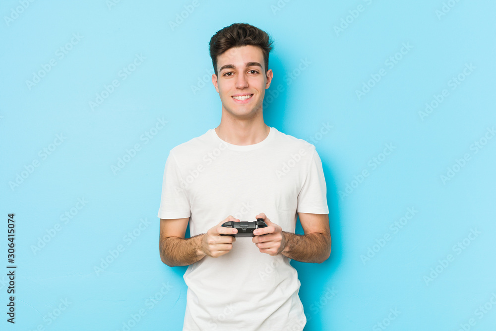 Young caucasian man playing videogames with game controller happy, smiling and cheerful.