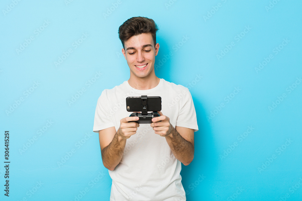 Young caucasian man playing videogames with phone happy, smiling and cheerful. Young caucasian man playing videogames with phone happy, smiling and cheerful.