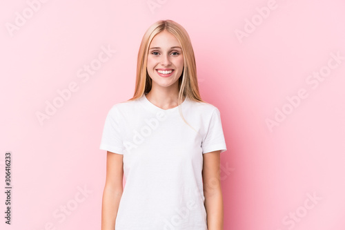 Young blonde woman on pink background happy, smiling and cheerful.