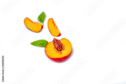 Slices of smooth-skinned ripe nectarines (peaches) with leaves isolated on a white background. Top view, flat lay, copy space for text.