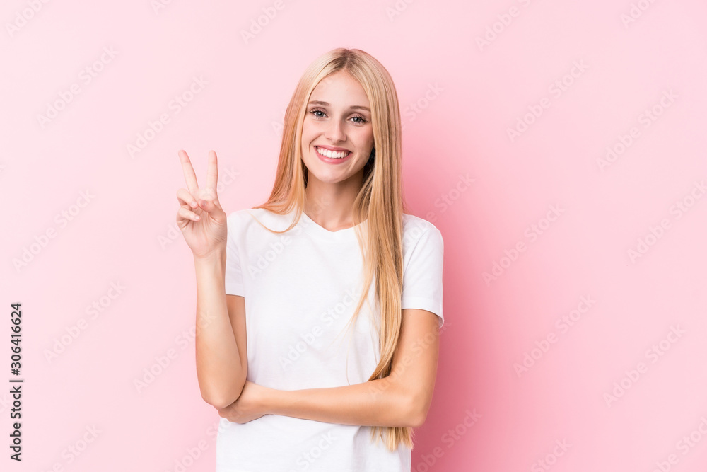 Young blonde woman on pink background showing number two with fingers. Young blonde woman on pink background showing number two with fingers.