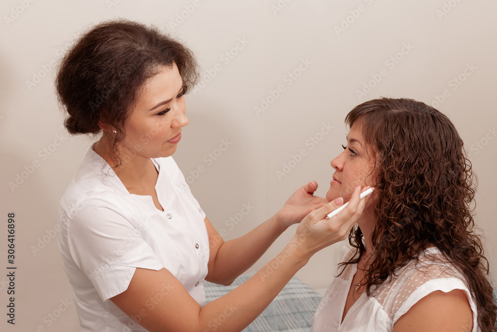 Beautician draws the contours of a white pencil on the face of the patient. Schematic marking before contouring. Close-up preparation of the face for cosmetic plastic surgery Beautician draws the contours of a white pencil on the face of the patient. Schematic marking before contouring. Close-up preparation of the face for cosmetic plastic surgery