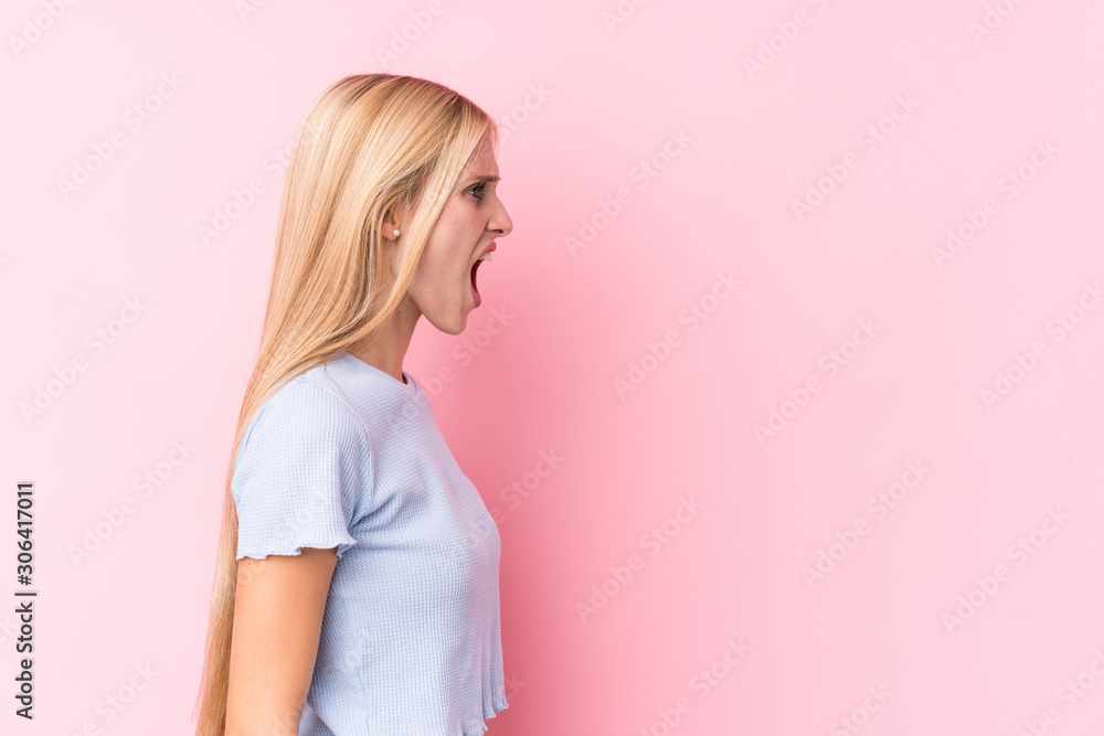 Young blonde woman on pink background shouting towards a copy space Young blonde woman on pink background shouting towards a copy space