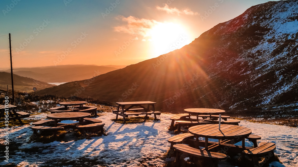 Kirkstone Pass, Lake District - Outside terrace with wooden chairs and tables at sunset on a cold winter day overlooking the snowy peaks in Cumbria, UK. 