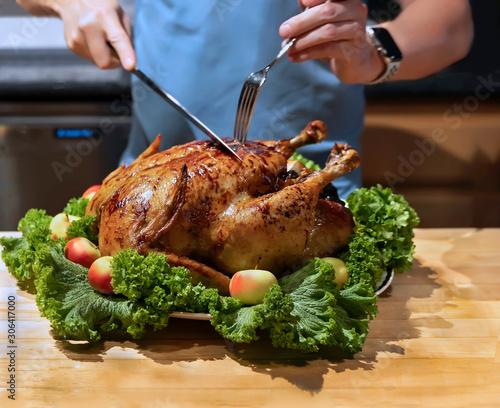 Hands cutting roast capon (turkey,chicken) on the kitchen table