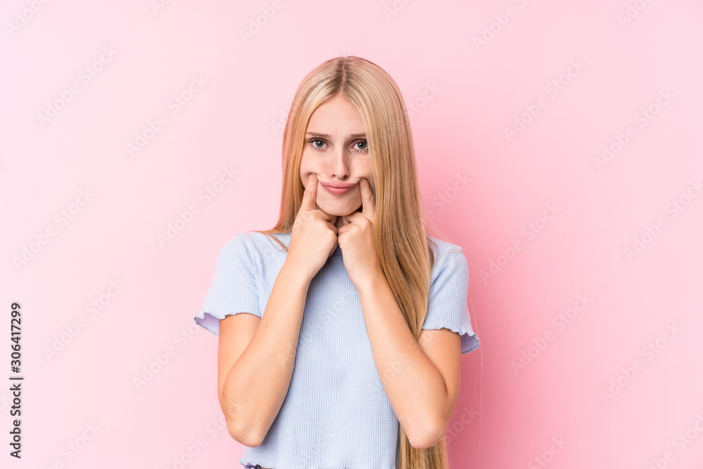 Young blonde woman on pink background doubting between two options. Young blonde woman on pink background doubting between two options.