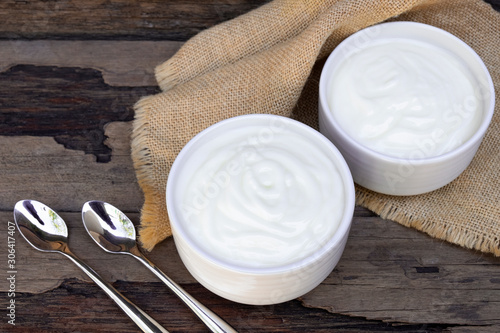 Yogurt greek white clean In bowl with spoon on a wooden background from top view.