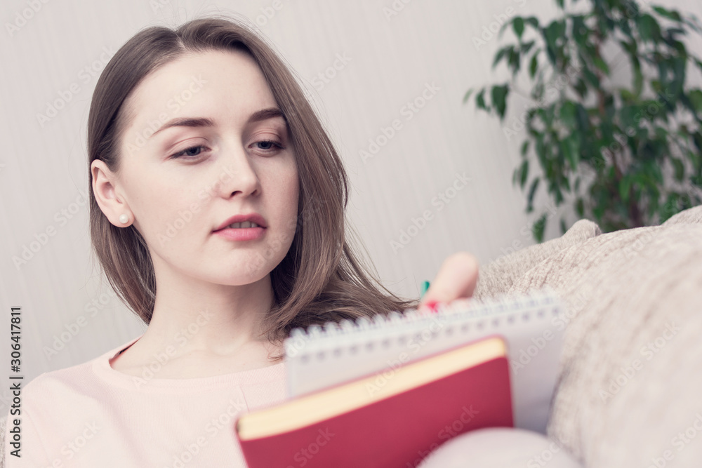 Young girl student doing his homework. Woman smiling and makes records. Portrait, close up, toned Young girl student doing his homework. Woman smiling and makes records. Portrait, close up, toned