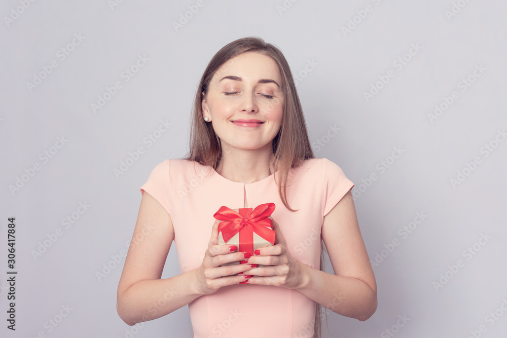 Beautiful woman received a gift. The girl is happy and closed her eyes with pleasure. Portrait, grey background, copy space, toned Beautiful woman received a gift. The girl is happy and closed her eyes with pleasure. Portrait, grey background, copy space, toned