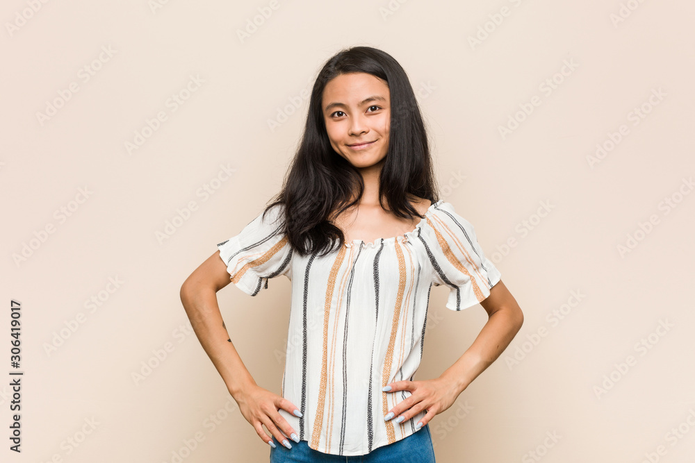 Young cute chinese teenager Young blonde woman wearing a coat against a pink background confident keeping hands on hips. Young cute chinese teenager Young blonde woman wearing a coat against a pink background confident keeping hands on hips.