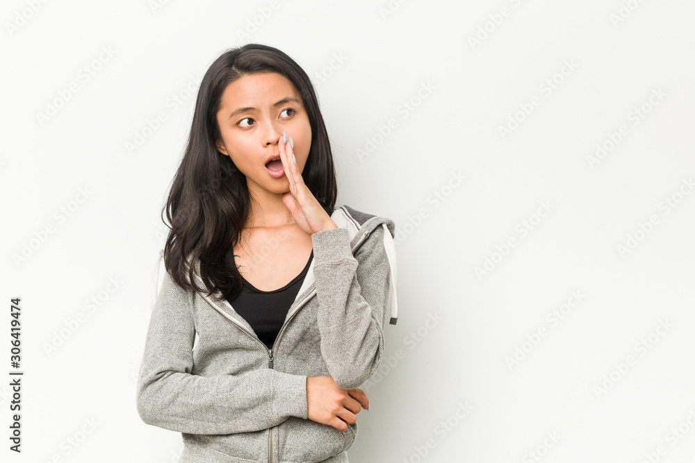 Young fitness chinese woman is saying a secret hot braking news and looking aside Young fitness chinese woman is saying a secret hot braking news and looking aside