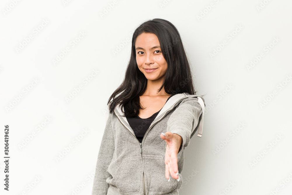 Young fitness chinese woman stretching hand at camera in greeting gesture. Young fitness chinese woman stretching hand at camera in greeting gesture.