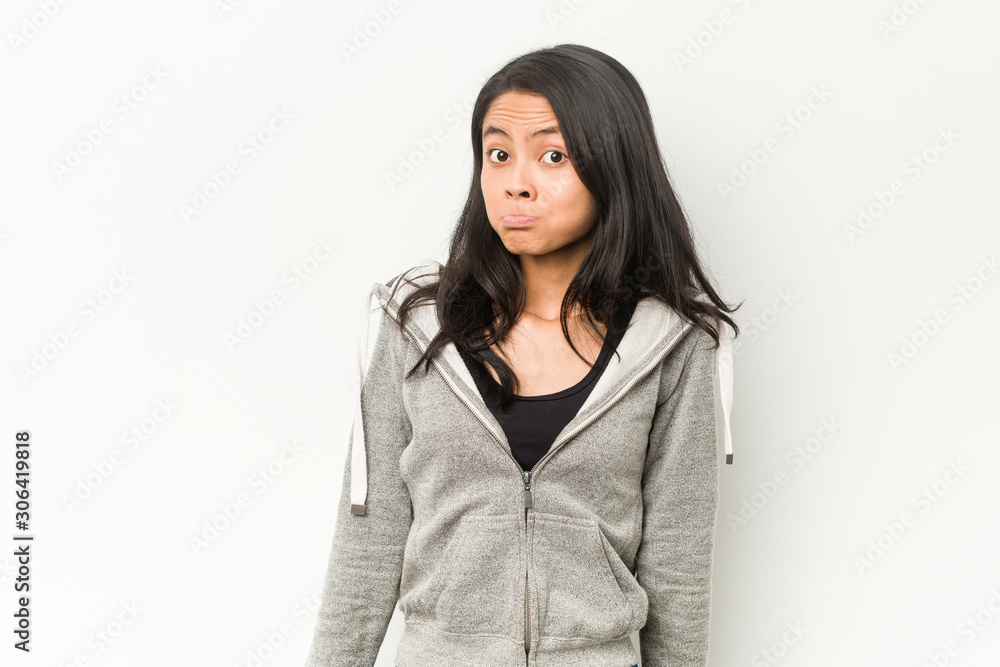 Young fitness chinese woman shrugs shoulders and open eyes confused. Young fitness chinese woman shrugs shoulders and open eyes confused.