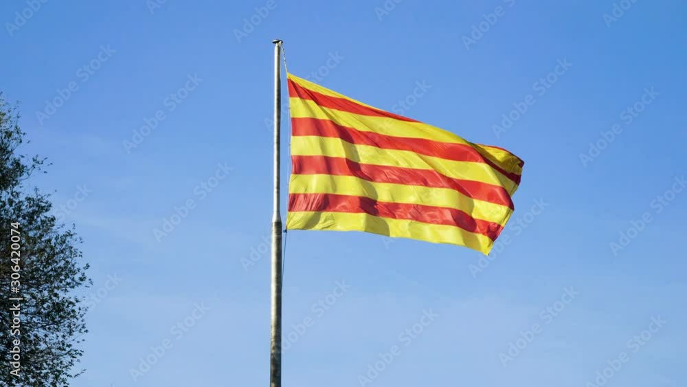 Close-up shot of the flag of Catalonia flying in the wind against blue sky. Barcelona. Spain. 4K Close-up shot of the flag of Catalonia flying in the wind against blue sky. Barcelona. Spain. 4K