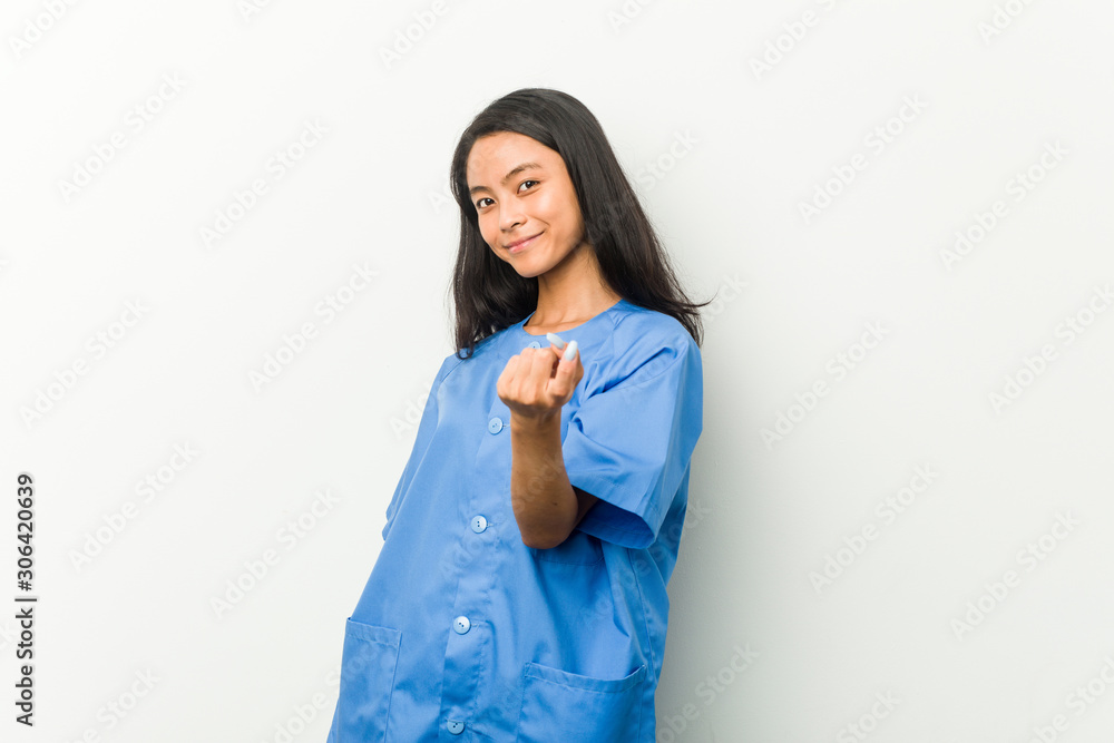 Young asian nurse woman pointing with finger at you as if inviting come closer. Young asian nurse woman pointing with finger at you as if inviting come closer.