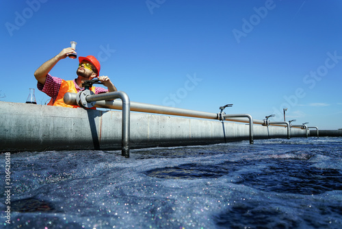 An engineer controlling a quality of water ,aerated activated sludge tank at a waste water treatment plant.  pollution  