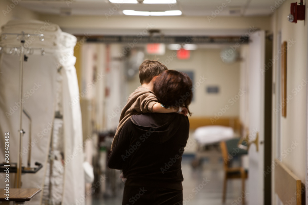 Mother carrying son in corridor at hospital Mother carrying son in corridor at hospital