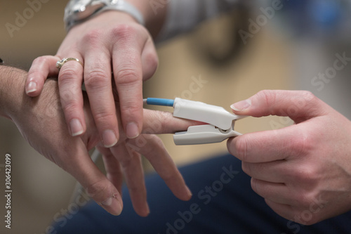 doctor applying pulse oximeter on patient finger at hospital